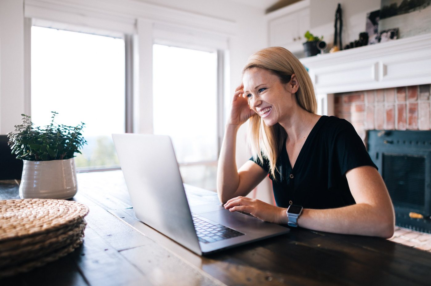 Carly Walton smiling at her laptop at a kitchen table